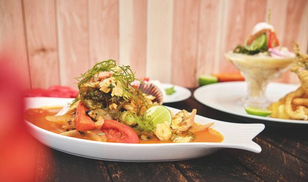 Nourriture péruvienne : appelée "Leche de tigre" et "sudado de mariscos", fruits de mer (sueur de poisson, pétoncles, crevettes, poulpe, escargot, mélangé avec des légumes et du jus épicé) vue de dessus. Concentration sélective - Photo, image