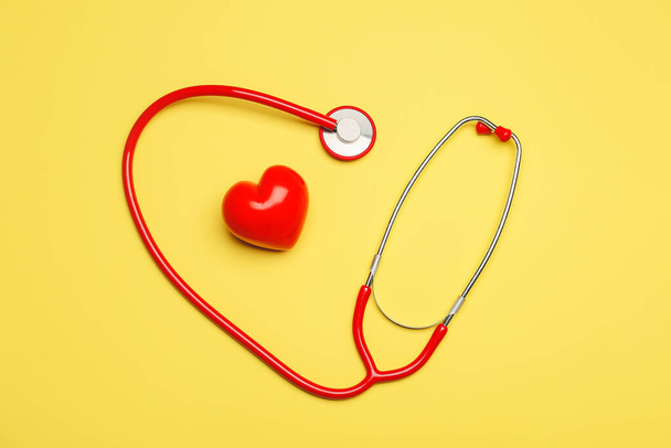 Piros szív sztetoszkóppal színes háttér - Fotó, kép