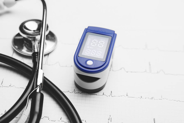 Pulse oximeter, stethoscope and cardiogram on white background - Foto, Imagen