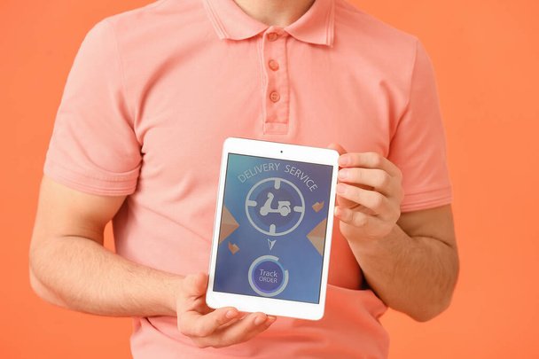 Hombre joven y tableta con la página abierta de la aplicación de servicio de entrega en el fondo de color - Foto, imagen