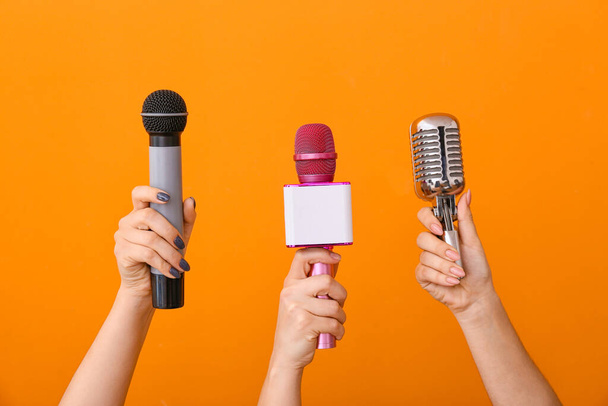 Female hands with modern microphones on color background - Photo, Image
