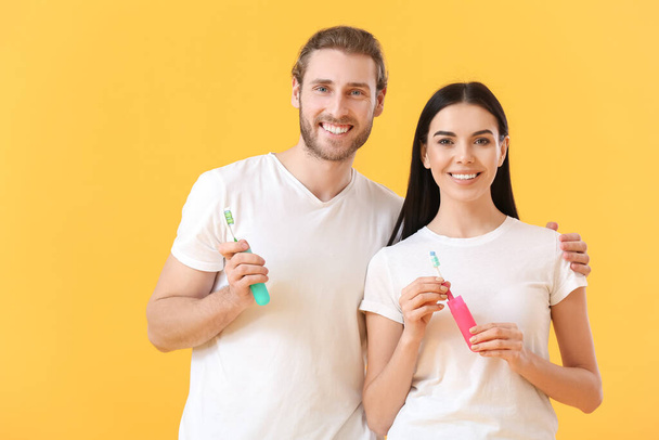 Mladý pár s kartáčky na zuby na barevném pozadí - Fotografie, Obrázek