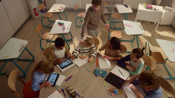 Schüler mit Polstern lernen am runden Tisch. Kinder nutzen digitale Tablets - Foto, Bild