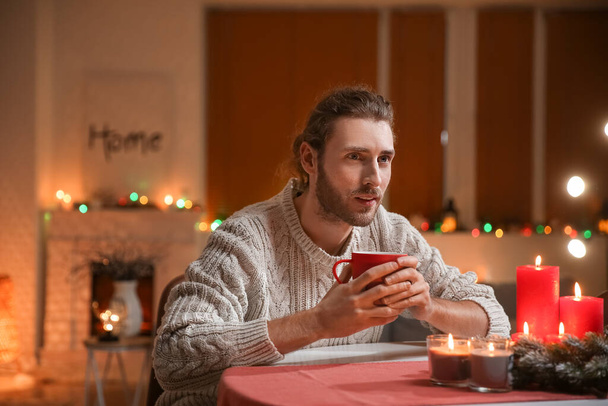 Hombre guapo bebiendo té caliente en casa en Nochebuena - Foto, Imagen