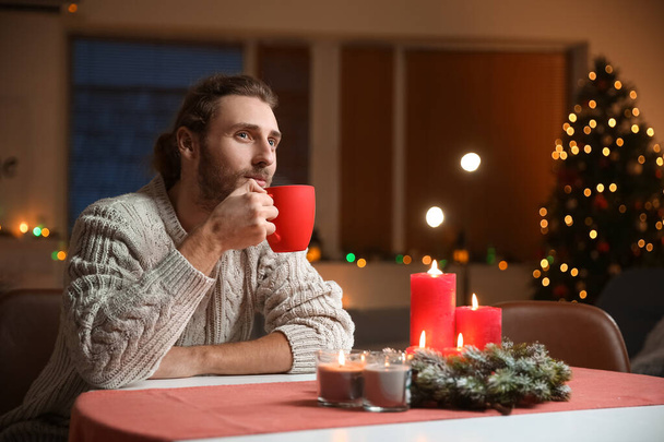 Όμορφος άντρας πίνει ζεστό τσάι στο σπίτι παραμονή Χριστουγέννων - Φωτογραφία, εικόνα