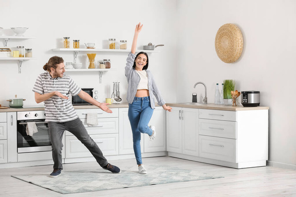 Happy young couple dancing in kitchen - Foto, afbeelding