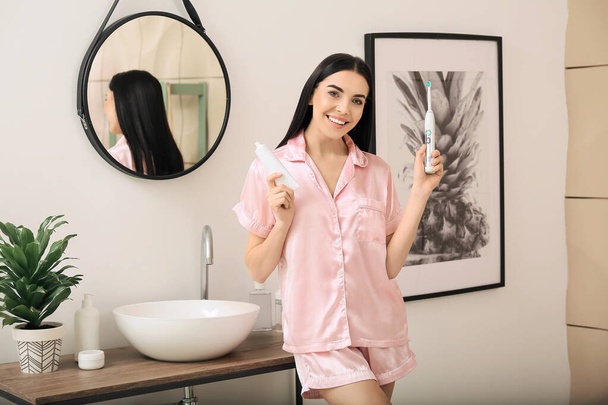 Fiatal nő fogkefével és paszta a fürdőszobában - Fotó, kép