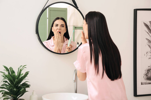 Stanco giovane donna lavarsi i denti in bagno - Foto, immagini
