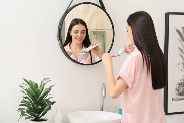 Молода жінка чистить зуби у ванній
 - Фото, зображення