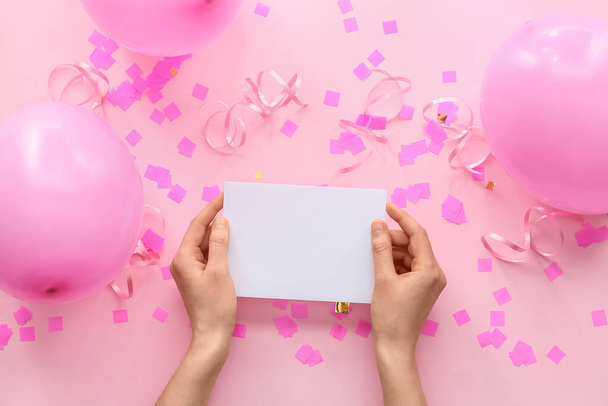 Female hands with blank paper sheet, air balloons and confetti on color background - Photo, Image