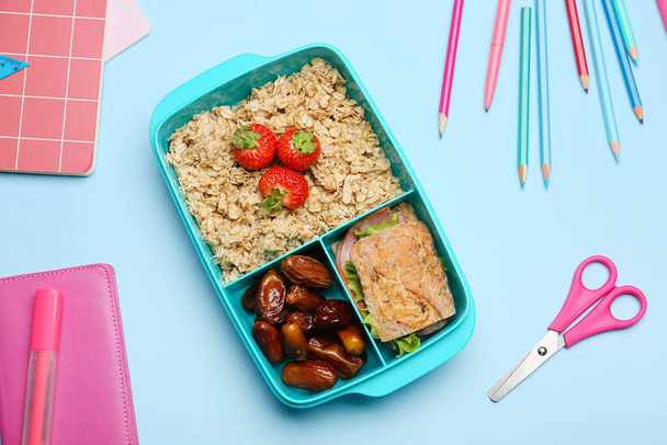 Обідня коробка зі смачною їжею та канцтоварами на кольоровому фоні
 - Фото, зображення