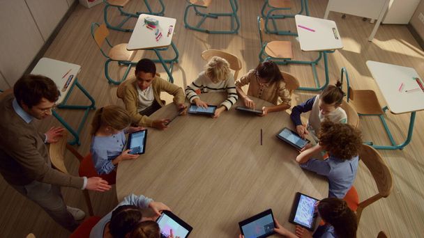Mannelijke leraar helpt studenten met tablet computers bij de les. - Foto, afbeelding
