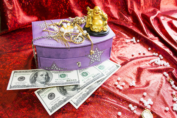 Коробка для украшений, долларов и золотого Будды на красном фоне
 - Фото, изображение