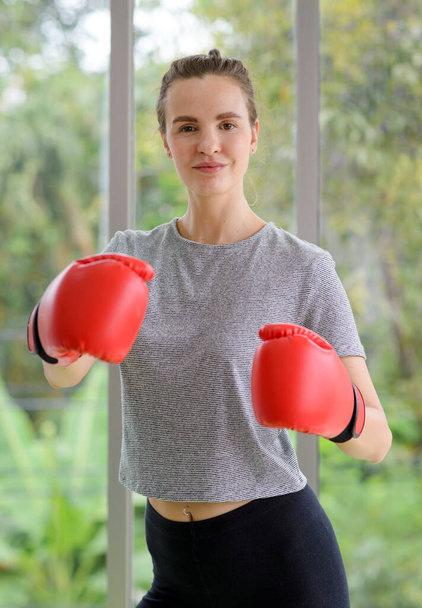 Ritratto di giovane donna sportiva in abbigliamento sportivo con guanti da boxe rossi colpito a pugni. concetto di stile di vita sano - Foto, immagini