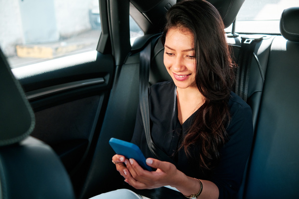 fiatal latin üzletasszony használ okostelefon autójában - Fotó, kép
