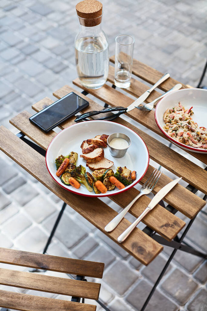 pollo a la parrilla con verduras con salsa en una mesa de madera en la terraza de un restaurante local - Foto, Imagen