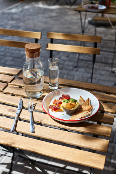 desayuno en la terraza restaurante local en aguacate por la mañana con huevo, tocino y tostadas - Foto, imagen