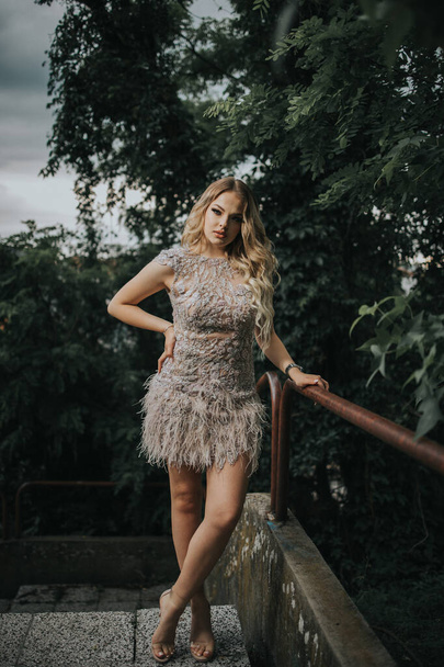 A vertical shot of a young stylish female in a cocktail dress posing outdoors - Foto, afbeelding