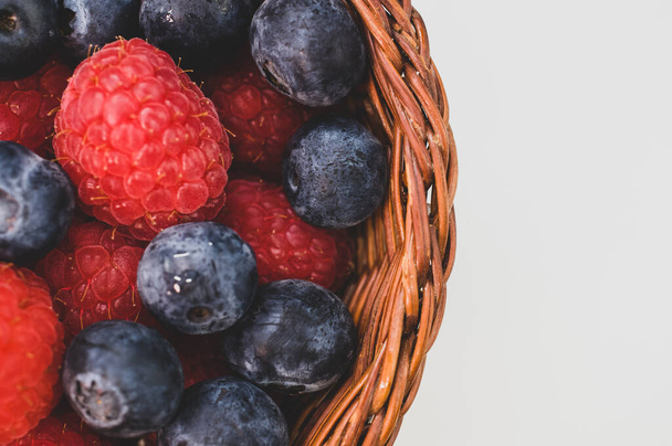 A closeup shot of blueberries raspberries in a basket - Foto, afbeelding