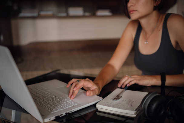 Молода азіатська студентка, яка використовує ноутбук, спілкується в Інтернеті. Затишне офісне робоче місце, віддалена робота, концепція електронного навчання. крупним планом руки
 - Фото, зображення