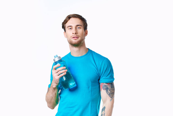 uomo in t-shirt blu con una bottiglia d'acqua in mano su sfondo bianco Copy Space - Foto, immagini