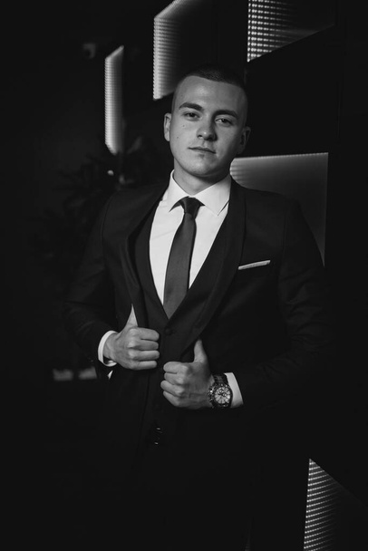 A grayscale shot of a young elegant Caucasian male wearing an expensive suit at an event - Фото, зображення