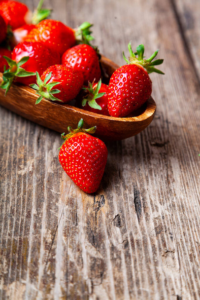 Ripe strawberries in a wooden bowl on a wooden background. - Photo, Image
