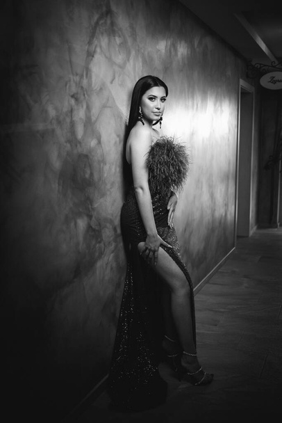 A grayscale shot of a glamorous caucasian female in a luxury evening dress with feathers - Photo, Image