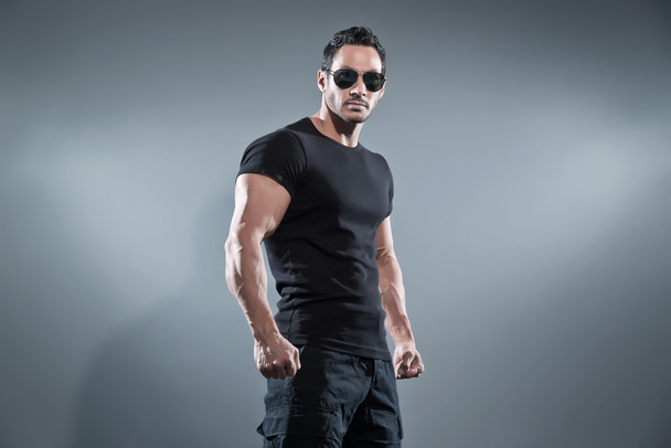 Kampf muskulöser Action-Held Mann trägt schwarzes T-Shirt mit Hose  - Foto, Bild