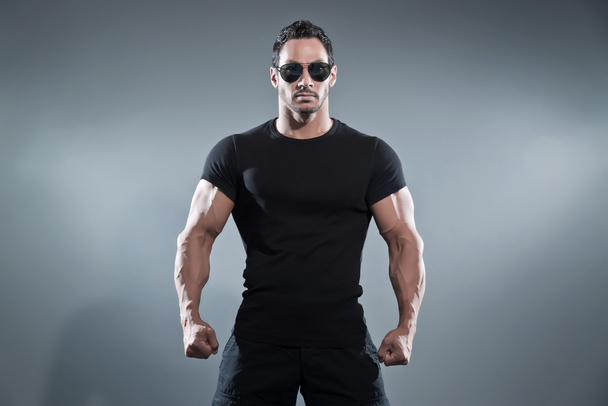 Combattimento muscoloso azione eroe uomo indossa nero t-shirt con pantaloni
  - Foto, immagini