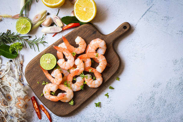 Shrimp peeled on wooden cutting board background on the table food kitchen, Fresh shrimps prawns seafood lemon lime with herbs and spice - Photo, Image