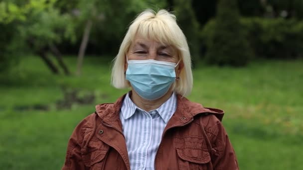 Influenssavirus levittää influenssaviruksilta ja taudeilta suojaavaa suojamaskia. Valkoihoinen 50-vuotias nainen, jolla on kirurginen naamio kasvoillaan julkisissa tiloissa. Terveydenhuolto. - Materiaali, video