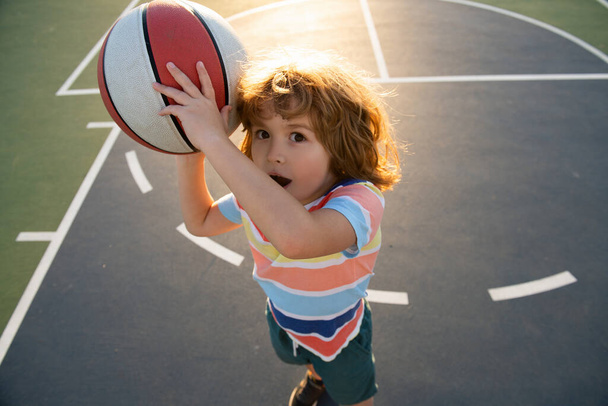 Little caucasian sports kid playing basketball holding ball with funy face. - Fotoğraf, Görsel