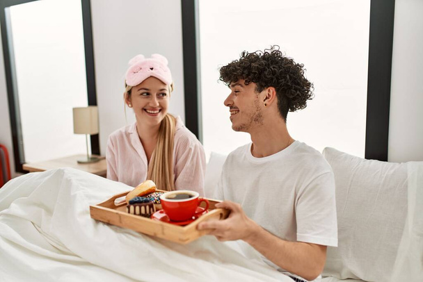 Молода красива пара посміхається щасливий сніданок на ліжку вдома
. - Фото, зображення