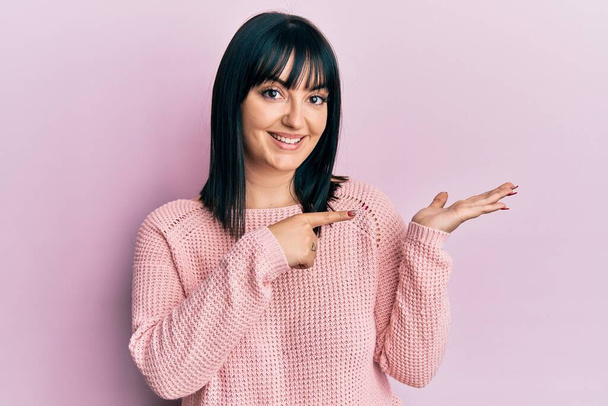 Young hispanic woman wearing casual clothes amazed and smiling to the camera while presenting with hand and pointing with finger.  - Φωτογραφία, εικόνα