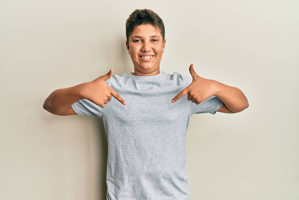 Teenager hispanic boy wearing casual grey t shirt looking confident with smile on face, pointing oneself with fingers proud and happy.  - Photo, Image