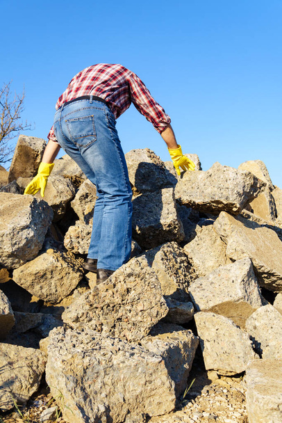 un hombre trabaja con un montón de piedras y pedazos rotos de hormigón, lleva escombros de construcción - Foto, Imagen