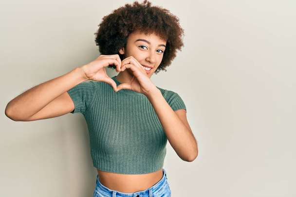 Jong Latijns-Amerikaans meisje draagt casual kleding glimlachend in liefde doen hart symbool vorm met handen. romantisch concept.  - Foto, afbeelding