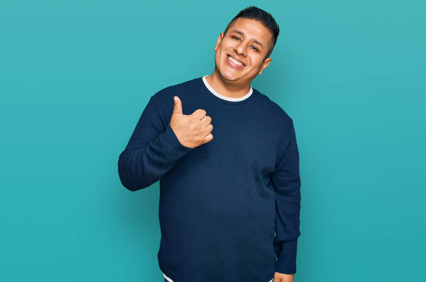 Young latin man wearing casual clothes doing happy thumbs up gesture with hand. approving expression looking at the camera showing success.  - Foto, Bild