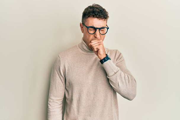 Hispanic young man wearing casual turtleneck sweater feeling unwell and coughing as symptom for cold or bronchitis. health care concept.  - Фото, изображение