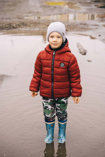 a child in boots walks through puddles - Foto, afbeelding