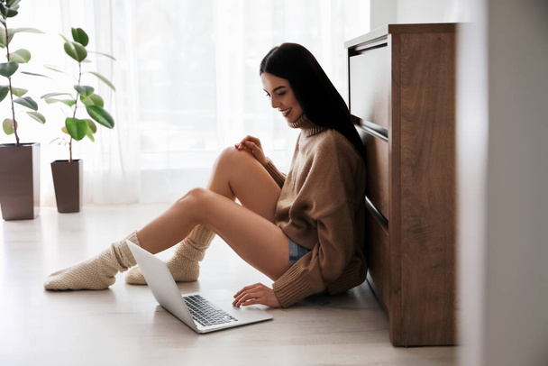 Woman with laptop sitting on warm floor at home. Heating system - Foto, immagini