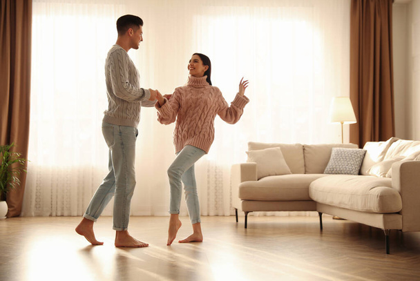 Happy couple dancing barefoot in living room. Floor heating system - Foto, Bild