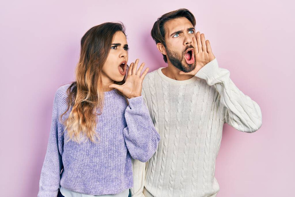 A fiatal spanyol házaspár alkalmi ruhát visel, kiabál és sikoltozik hangosan egymás mellett, kéz a kézben. kommunikációs koncepció.  - Fotó, kép