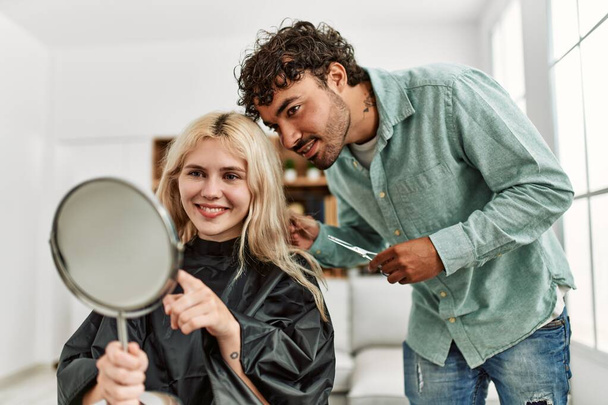 Young man cutting hair to his girlfriend at home. - Foto, Bild