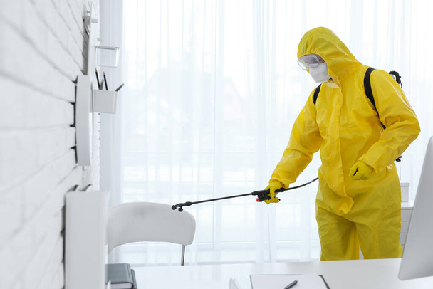Employee in protective suit sanitizing office. Medical disinfection - Foto, Bild
