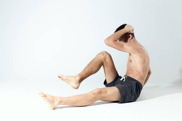  exercícios jovem atleta em shorts cinza e um treino de fitness torso inflado - Foto, Imagem