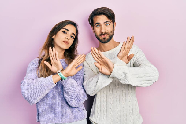 Young hispanic couple wearing casual clothes rejection expression crossing arms doing negative sign, angry face  - Photo, Image