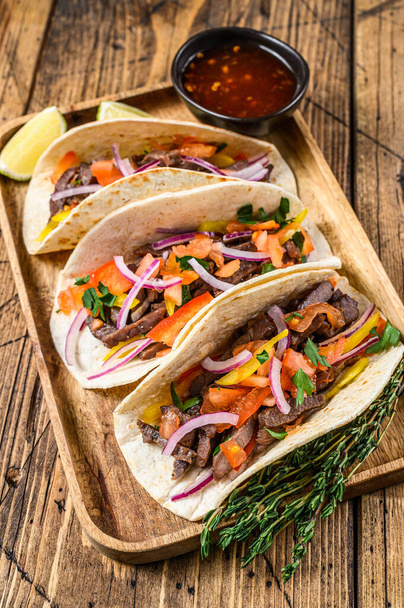 Tacos mit Rindfleisch, Zwiebeln, Tomaten, Paprika und Salsa. Mexikanisches Essen. Holzuntergrund. Ansicht von oben - Foto, Bild