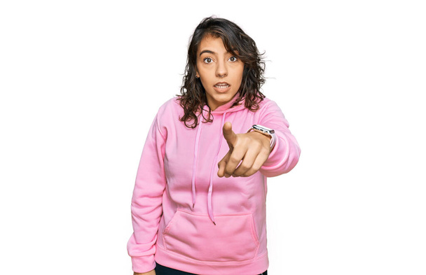Fiatal spanyol nő alkalmi pulóvert visel, elégedetlen és frusztrált a kamera előtt, dühös és dühös rád.  - Fotó, kép